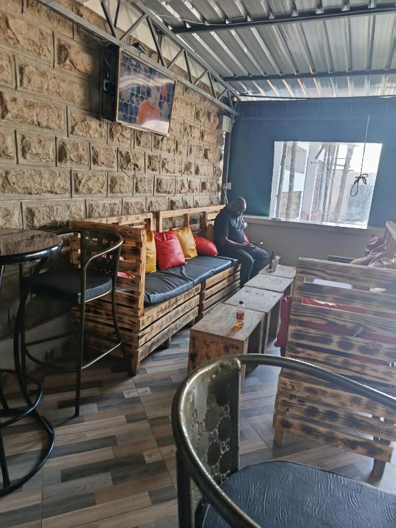 a man sitting on a couch in a room at J & J Olosho Hotel in Kiserian