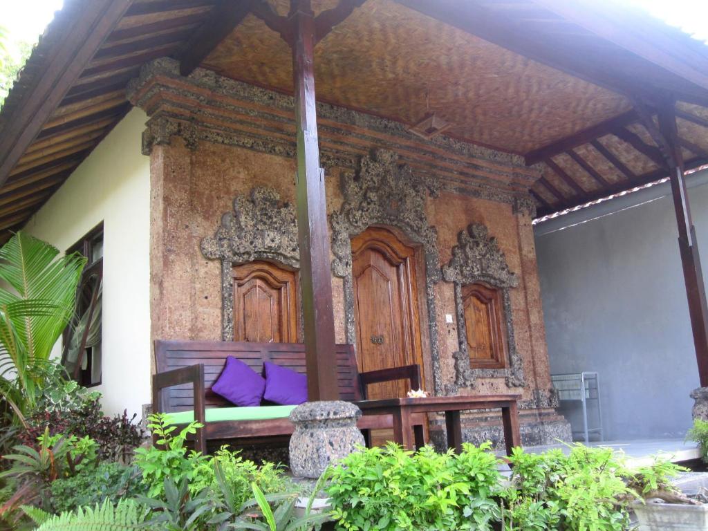 un porche con un banco con almohadas moradas en Galang Kangin Bungalows 2, en Amed