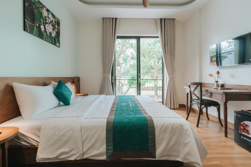 a bedroom with a bed and a desk and a window at November House in Thôn Kim Long (1)