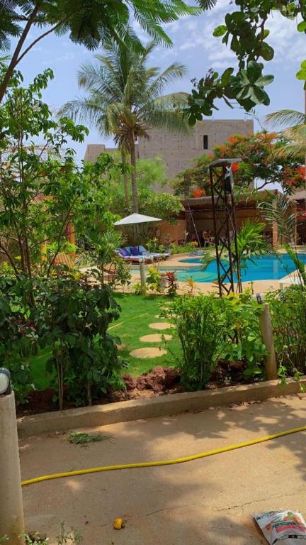 a garden with a swimming pool and palm trees at Villa Symphonie Saly in Saly Portudal