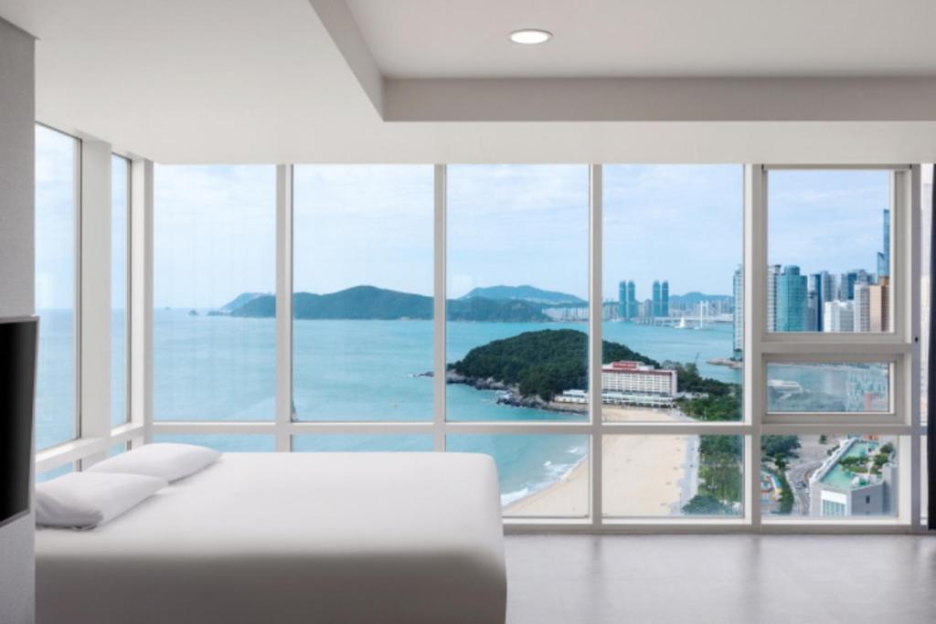 a bedroom with a bed and a view of the ocean at Sun Cloud Hotel in Busan