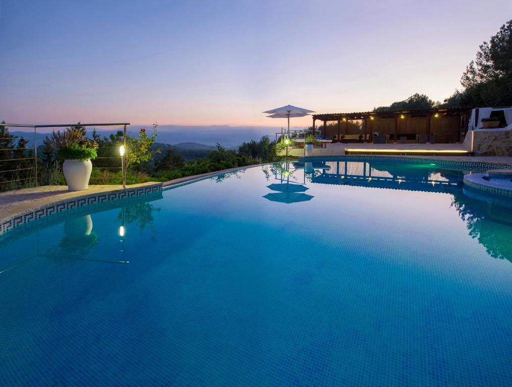 a large blue swimming pool with a sunset in the background at Villa Buscastells in Santa Gertrudis de Fruitera