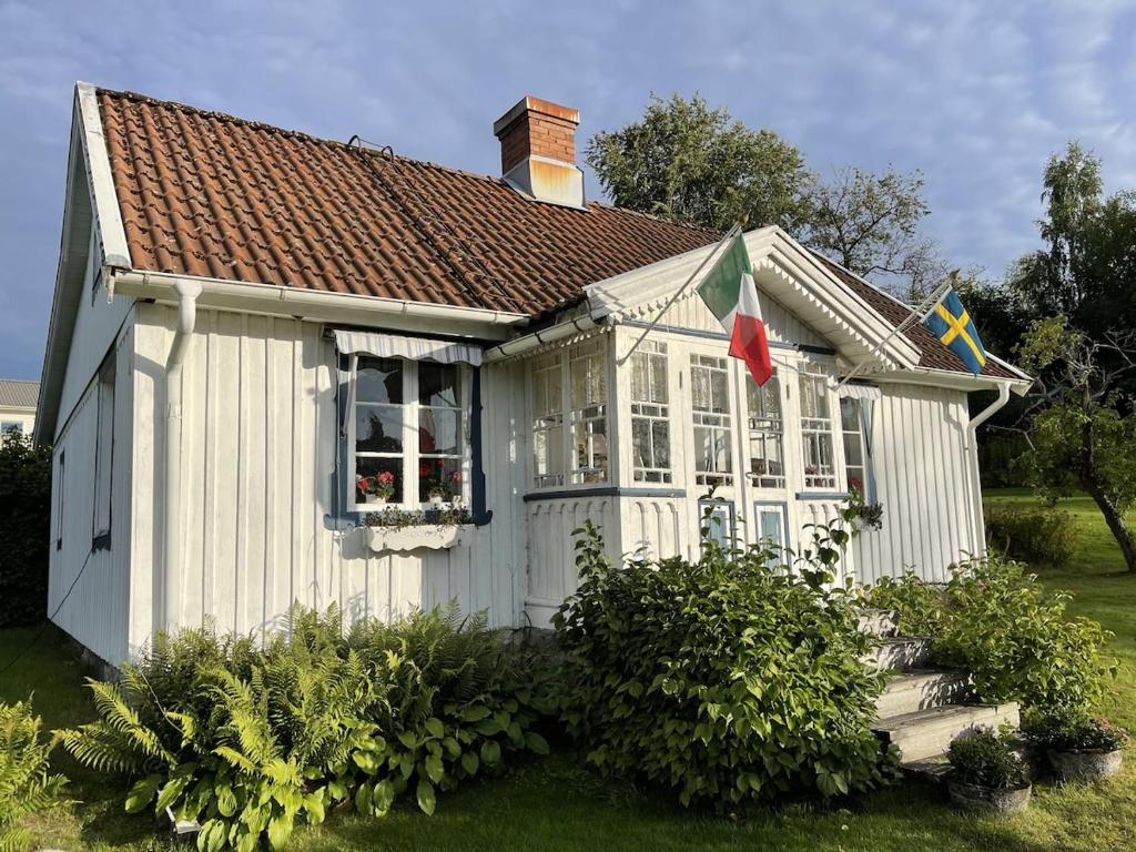 a small white house with a window and a flag at Sjöberg's Cosy Cottage in Ljungby