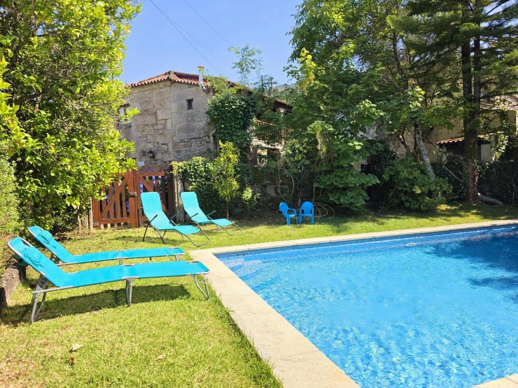 a swimming pool with blue chairs and a house at Villa Vetusta in Penso