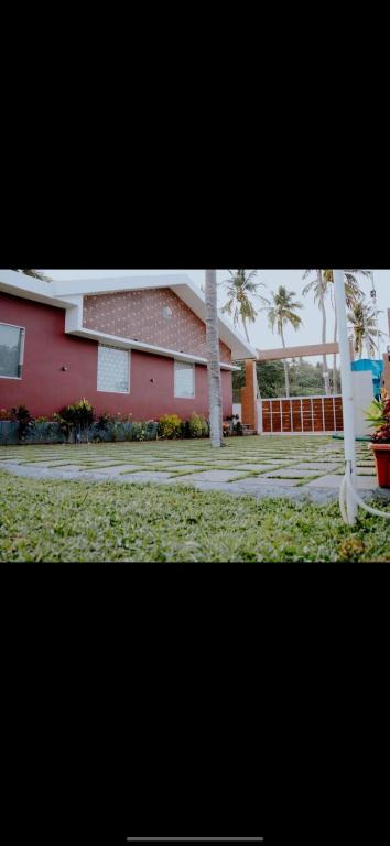 a red house with palm trees in front of it at Corniche inn river view villa 2 BHK in Kāsaragod