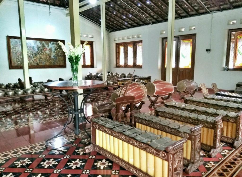 a room with chairs and tables and a vase of flowers at Omah Pitoe Yogya Homestay in Yogyakarta