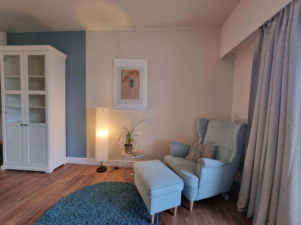 a living room with a blue chair and a stool at Ghent Business Flat in Ghent