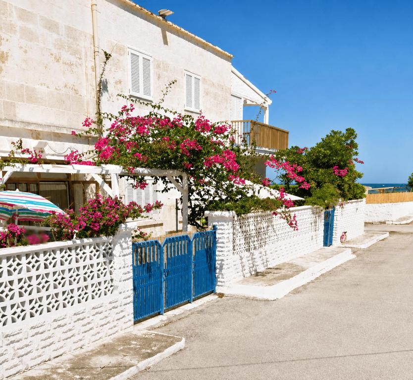 a white house with pink flowers on a fence at Pietra & Mare Ostuni in Villanova di Ostuni