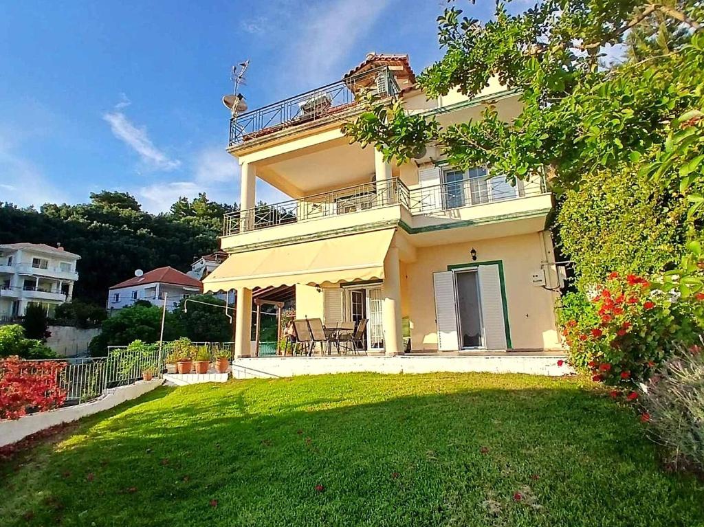 a large yellow house with a green yard at Villa Tsiggos in Kanallákion