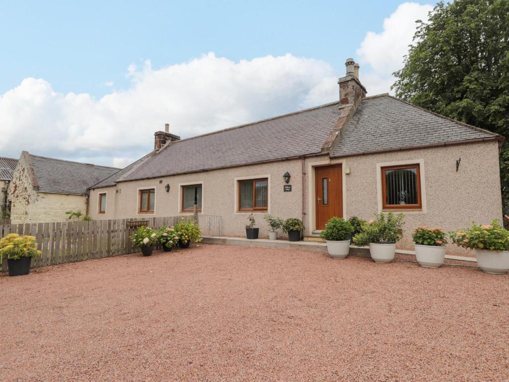 a house with potted plants in front of it at Millmoss Cottage in Turriff