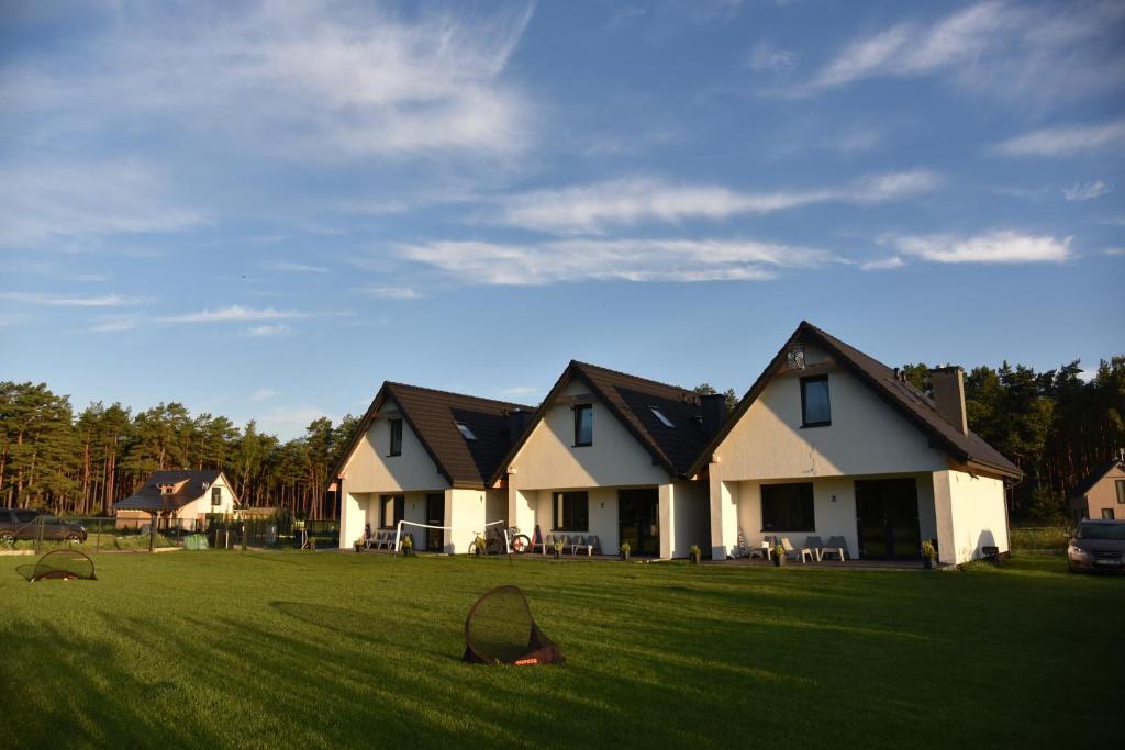 a large house in a yard with a green field at Lubiatówki in Lubiatowo