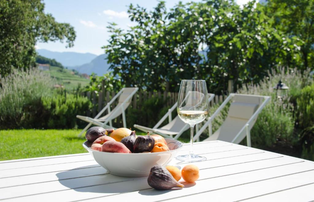 a bowl of fruit and a glass of wine on a table at cottage lavanda e rosmarino in Lavis
