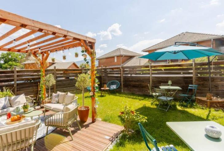 a backyard with a wooden deck with a table and an umbrella at Villa L'Epicléa, Chorges, entre lac et montagnes in Chorges