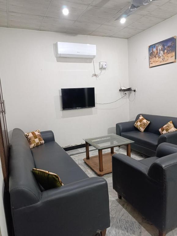 a living room with two couches and a tv at Alnoor Lodgings in Rabwāh