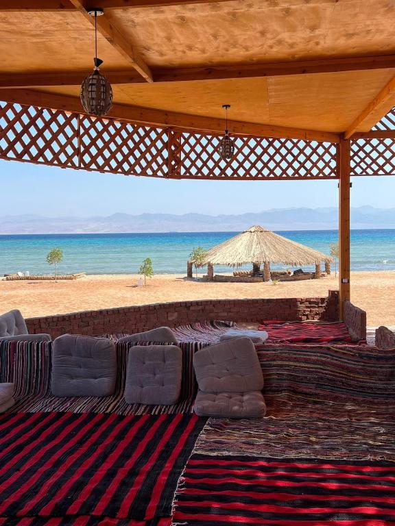 a view of a beach with chairs and an umbrella at Marhaba Camp in Nuweiba