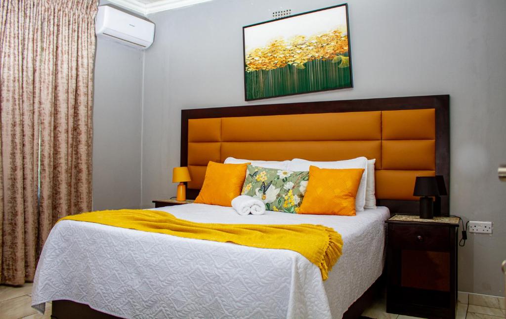 a bedroom with a large bed with an orange headboard at Ledula Guesthouse in Ramotswa