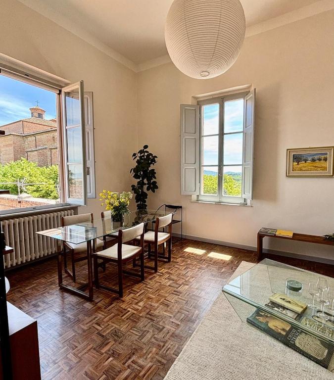 a living room with a table and chairs and windows at Le Finestre in Città della Pieve