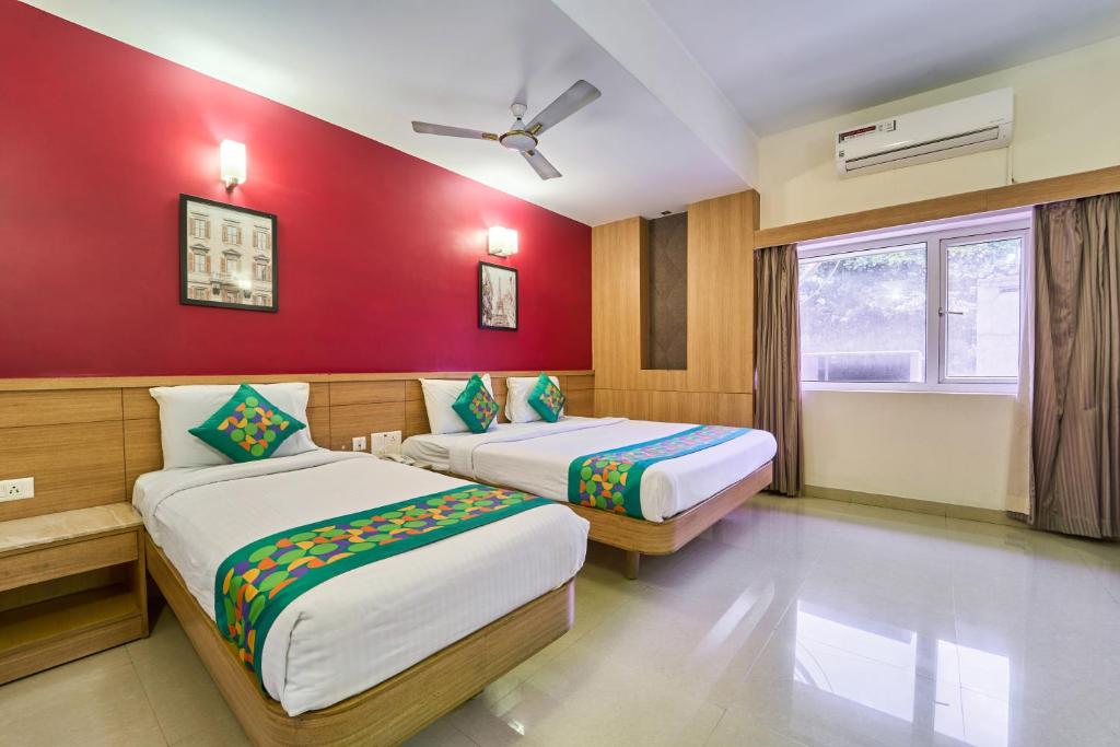 a bedroom with two beds and a red wall at Treebo ESS Grande in Coimbatore