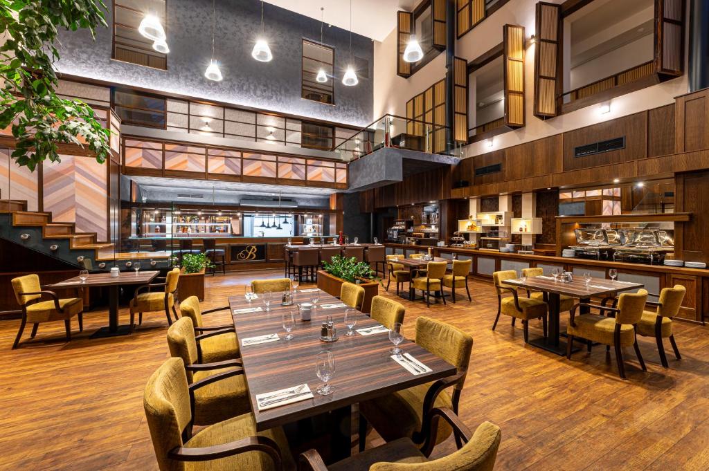 a restaurant with tables and chairs and a bar at Hotel Baltaci Atrium in Zlín