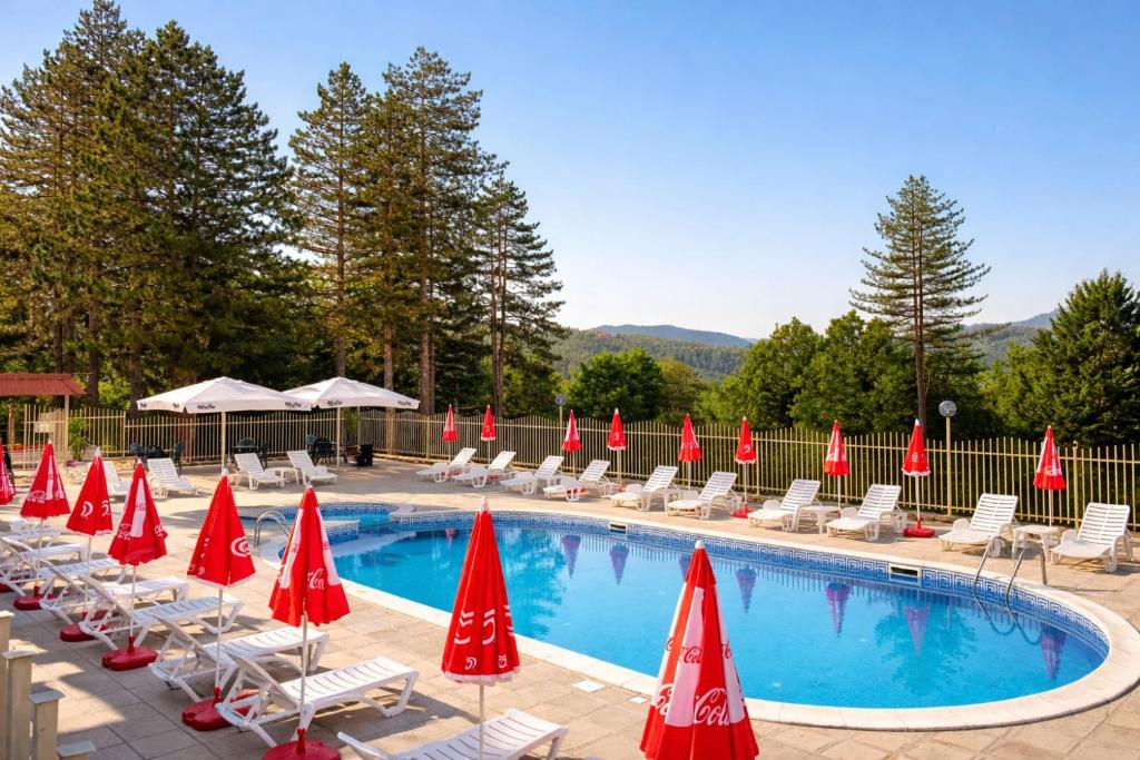 a pool with lounge chairs and red umbrellas at Hotel Velista in Voneshta Voda