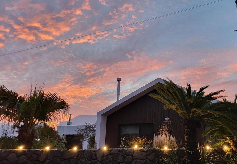 a house with a sunset in front of a building at Jeju Gallery House in Jeju