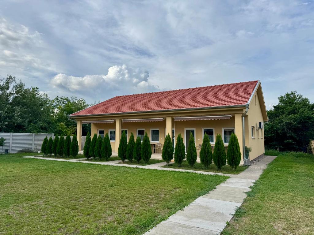 a house with a red roof and a row of trees at Primera Apartments in Palić
