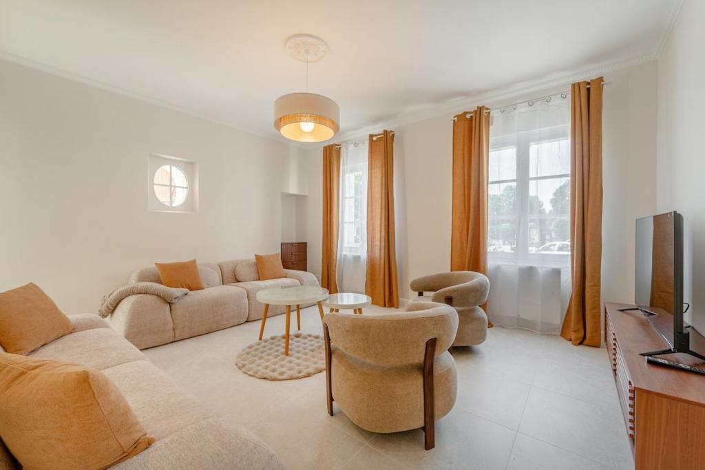 a living room with a couch and chairs and a tv at Maison Sophie for 10 guests in Pierrefonds