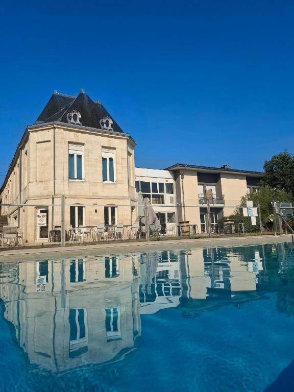 an old building with its reflection in a pool of water at Green Hôtels Bordeaux Arena in Latresne
