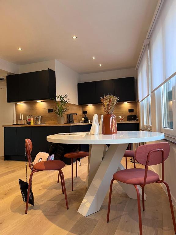a kitchen with a white table and some chairs at Cosy Of John Cockerill in Seraing