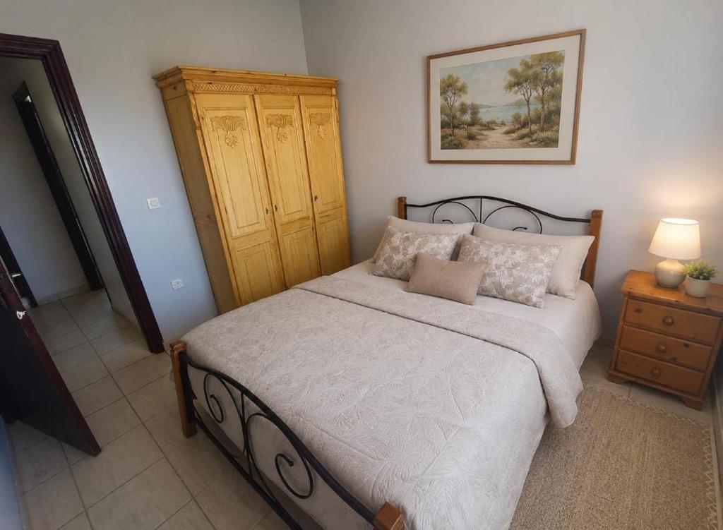 a bedroom with a large bed and a wooden cabinet at Raha-26 in Al Ghar