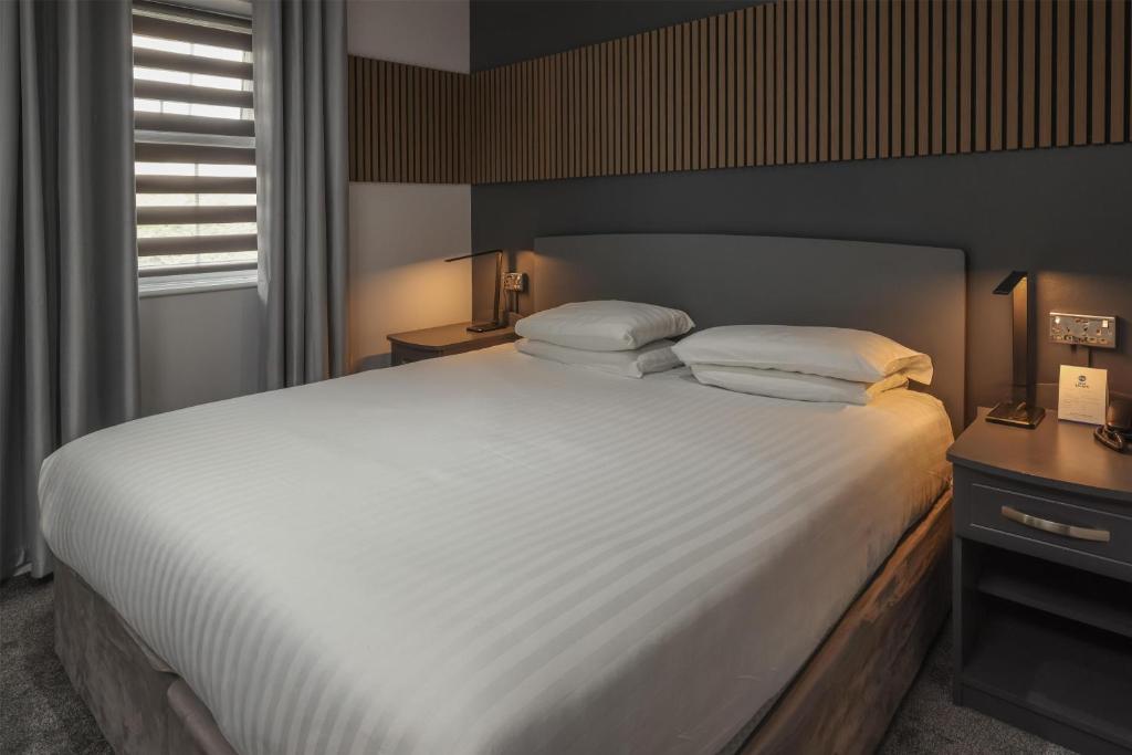 ein Schlafzimmer mit einem großen Bett mit weißen Laken und Kissen in der Unterkunft Best Western Claydon Hotel in Ipswich