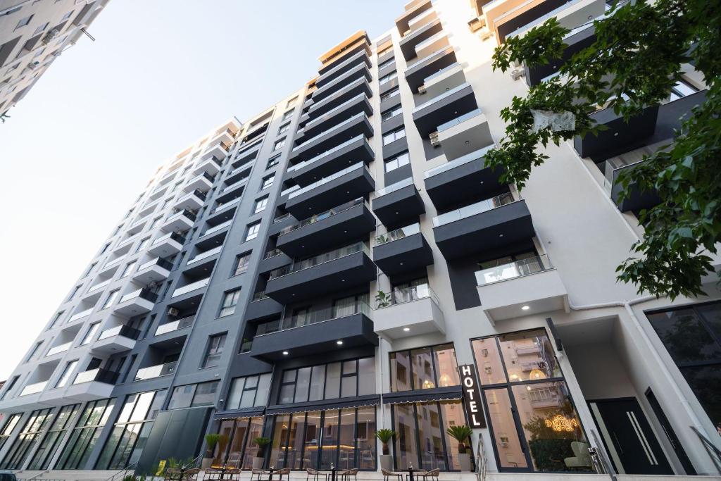 a tall white building with black windows at Hotel Digreis in Vlorë