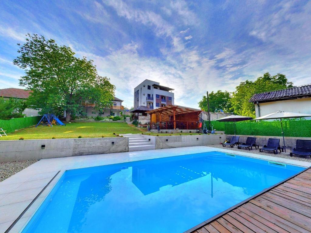 a large swimming pool in a yard with a house at Apartmani Maslačak in Vrdnik
