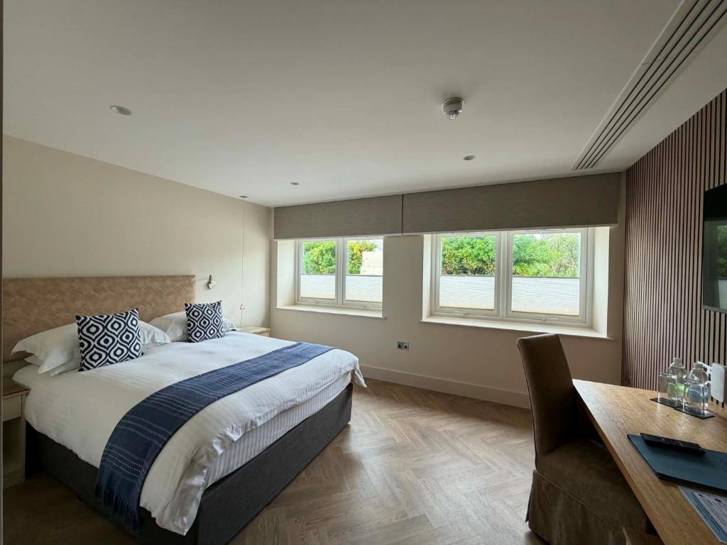 a bedroom with a bed and a desk and windows at Cobo Bay Hotel in Castel