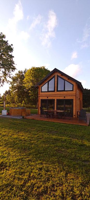 a wooden house with glass windows on a grass field at Mazurska Puszcza domek pod klonem z balią ogrodową in Budy