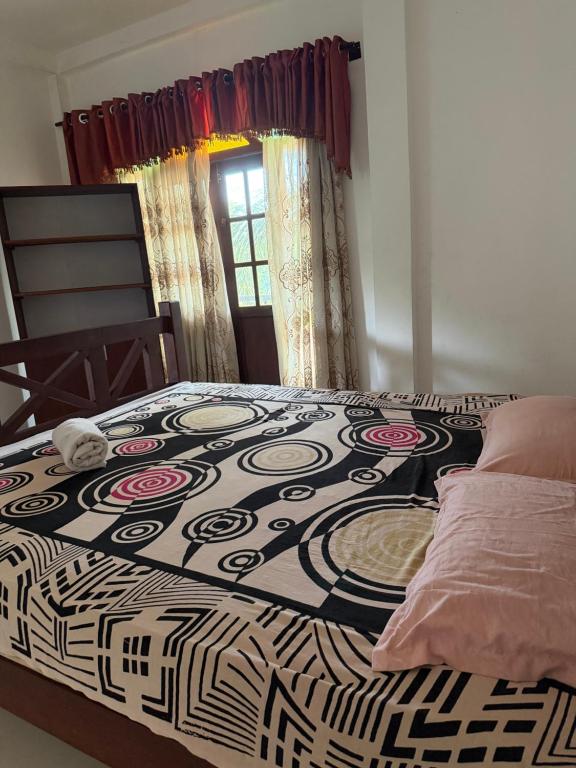 a bedroom with a black and white bed with a window at Nuwanma in Halpatota