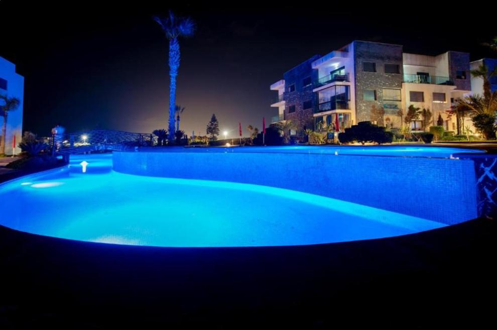 a large blue swimming pool at night at Modern Apartment with Pool & Sea View in Casablanca