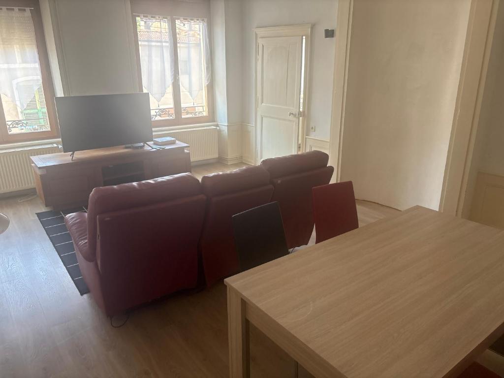a living room with a couch and a table and chairs at Belle appartement in Saint-Mihiel