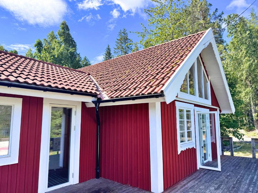 a red house with white windows and a roof at Stuga Gösjön in Berga