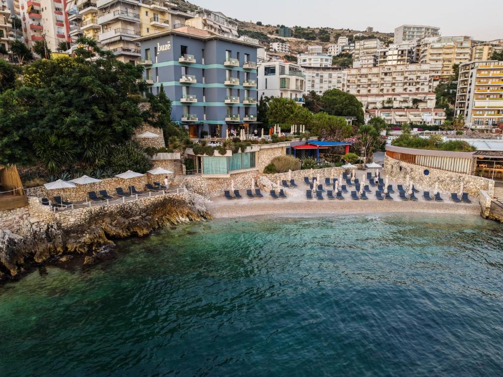 a beach with a bunch of chairs and buildings at Buzë Boutique Hotel in Sarandë