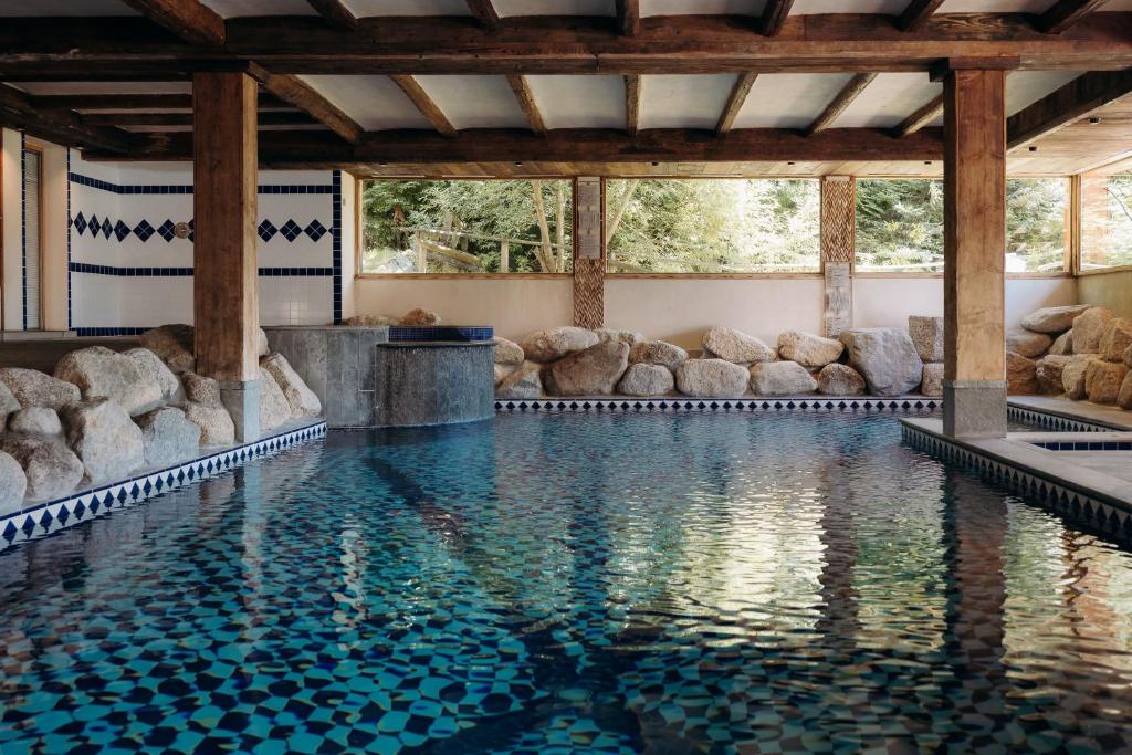 a swimming pool with rocks in the middle at Les Grands Montets Hotel & Spa in Chamonix