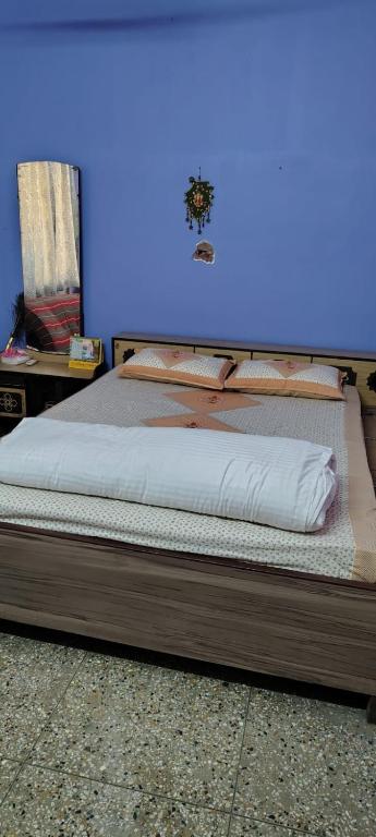 a bed in a room with a blue wall at Anand Vihar in kolkata