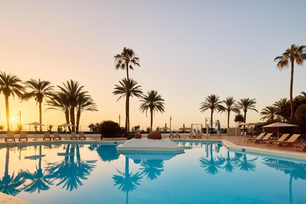 a swimming pool with palm trees in the background at SOL by Meliá Tenerife in Playa de las Americas