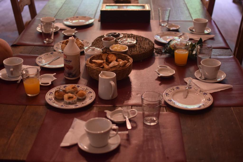 una mesa con platos de comida y vasos de zumo de naranja en Posada Niña Juana en Villa Dolores