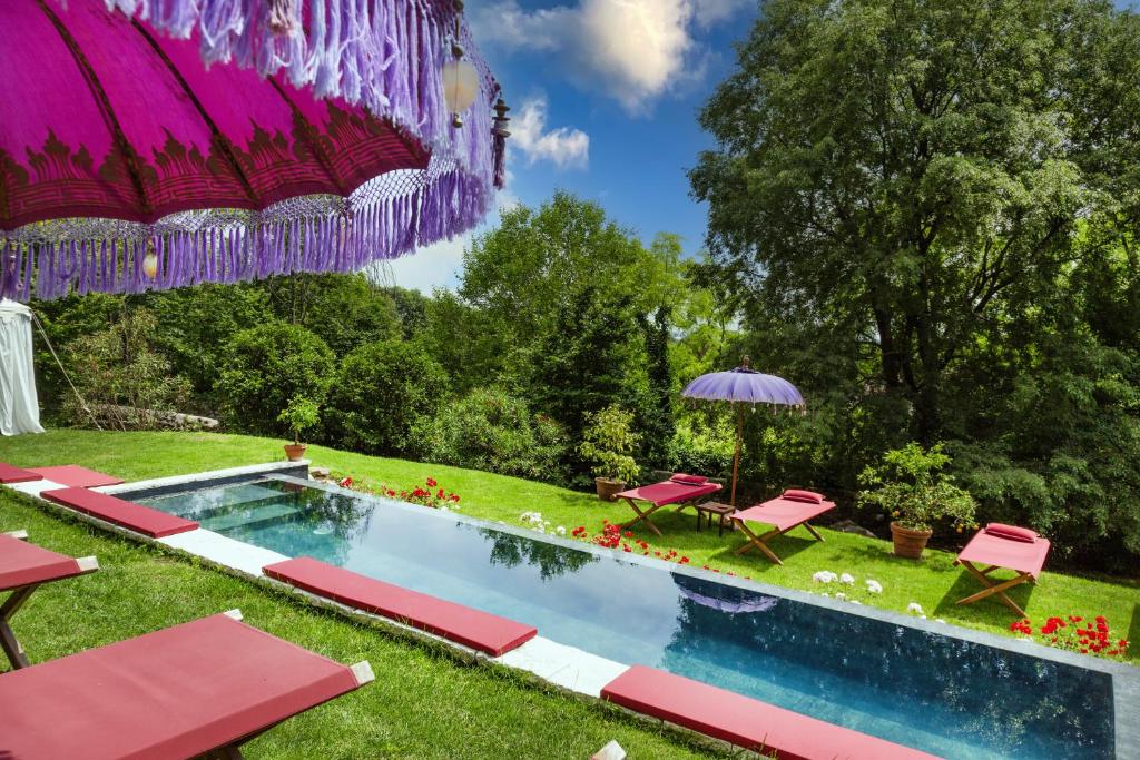 a swimming pool with pink chairs and an umbrella at Villa Verecondi Scortecci in Colle Umberto