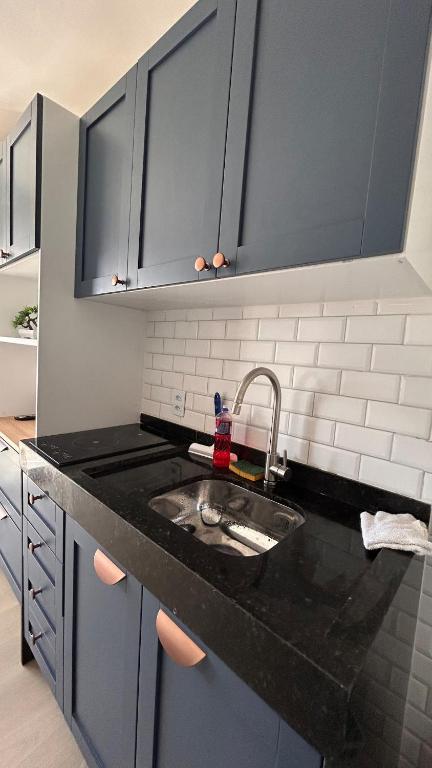 a kitchen with a sink and black counter top at Studio com sacada, piscina e academia a 25 min Aeroporto GRU in São Paulo
