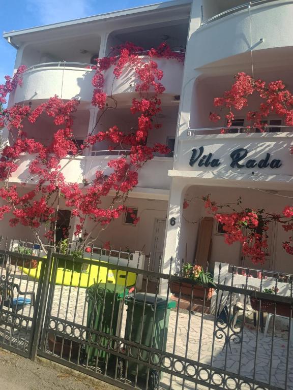 a building with red flowers in front of a building at Vila Rada in Čanj