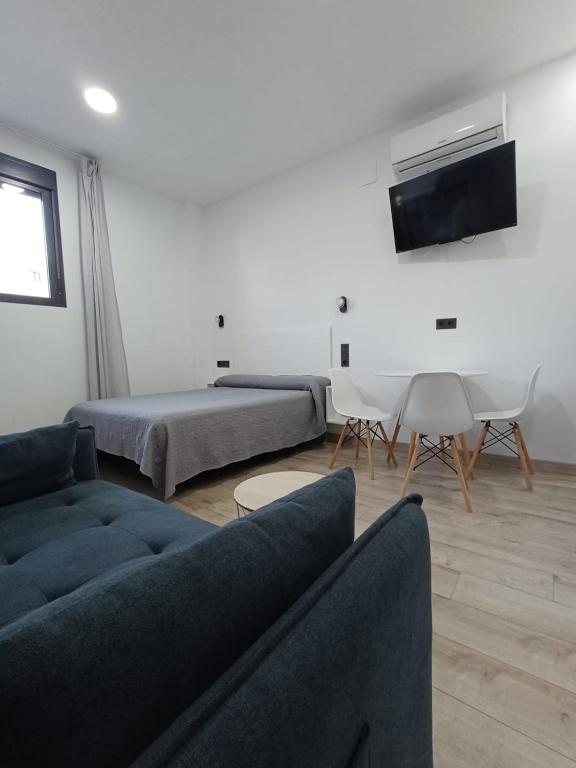 a living room with a couch and a bed and a tv at Medea Suites Apartamentos in Mérida
