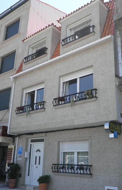 a gray building with balconies and flowers on it at Pensión Chiquilla in O Grove