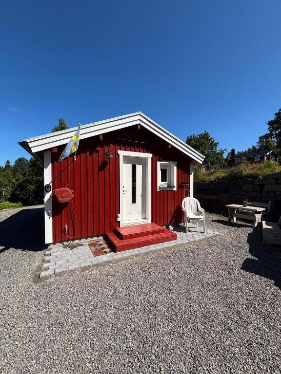 a red shed with a white door and a chair at Ugglan' in Undenäs